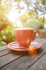 red coffee cup on wooden table with morning light
