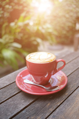 red coffee cup on wooden table with morning light