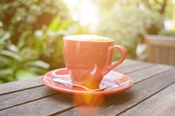 red coffee cup on wooden table with morning light