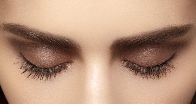 Perfect shape of eyebrows, brown eyeshadows and long eyelashes. Closeup macro shot of fashion smoky eyes visage