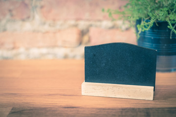 Blank blackboard on wood table top at blur brick background in r