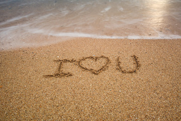 i love you written at the sand beach and on top soft wave. valentines day