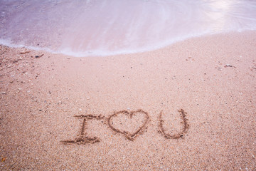 i love you written at the sand beach and on top soft wave. valentines day