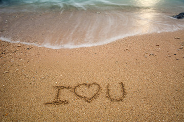i love you written at the sand beach and on top soft wave. valentines day