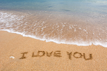 i love you written at the sand beach and on top soft wave. valentines day