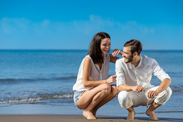 Romantic young couple draw shapes in the sand while on honeymoon.