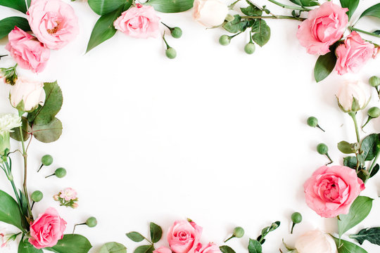 Round frame made of pink and beige roses, green leaves, branches on white background. Flat lay, top view. Valentine's background