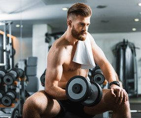 Fototapeta na wymiar Handsome confident young man with weights