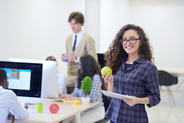 Portrait of pretty young woman eating an apple and holding tablet in her office.