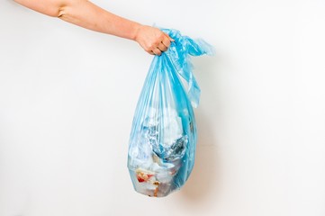 Female hand holding blue garbage bag