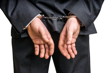 Arrested businessman in handcuffs with hands behind back