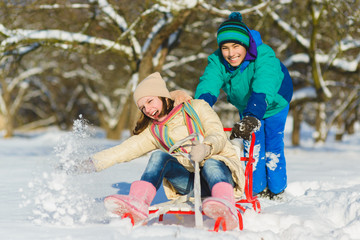 Happy boy and girl sledding in winter outdoor