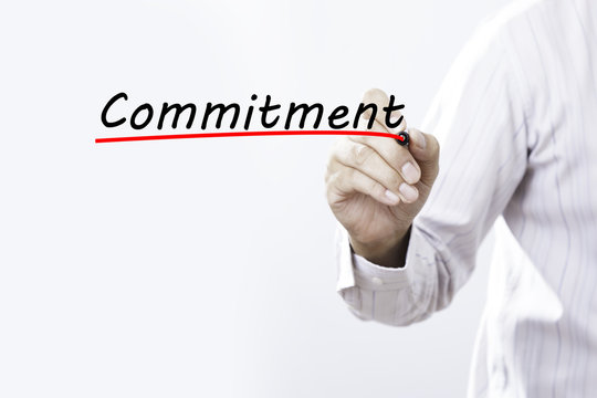Businessman hand writing inscription "Commitment" with marker, c
