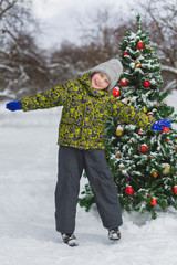 Cute little preschool boy jumping or playing near christmas tree outdoor