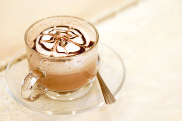 A glass of hot latte coffee with cream and chocolate art 