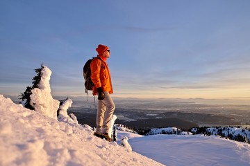 Man snowshoeing on mountain top watching sunset. Mount Seymour Provincial Park. Vancouver. British Columbia. Canada.