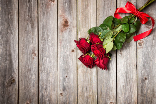 bouquet of red roses with bow on wood background. Valentines Day