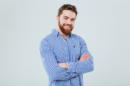 Happy handsome young man standing with arms crossed