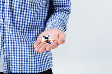 Man in checkered shirt standing and holding pills