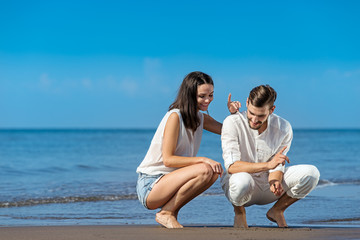 Fototapeta premium Romantic young couple draw shapes in the sand while on honeymoon.
