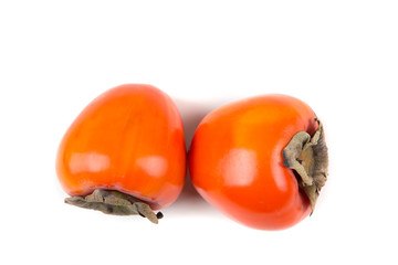 Two whole persimmmons isolated on a white background