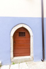 Traditional picturesque Mediterranean architecture at medieval town Vrbnik on Krk island, Croatia. View of arched wooden door, blue wall and inclined narrow alley.