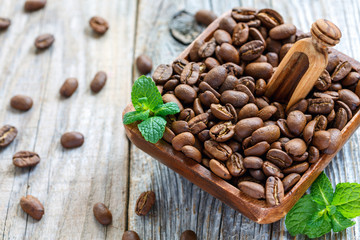 Coffee beans and wooden scoop in a bowl.