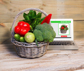 On-line shopping concept. The basket of vegetables purchased via the Internet, laptop 