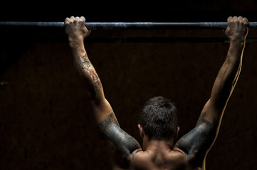 Muscular strong man doing pull ups on bar