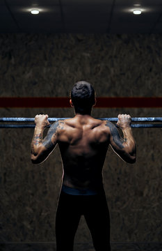 Back view male muscular athlete doing pull up