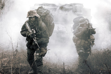 Jagdkommando soldiers Austrian special forces and tank moving on terrain in the fog. They are ready...