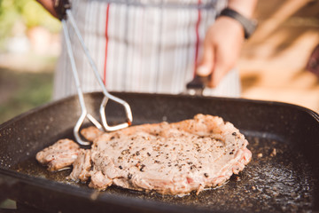 Men are cooking beef steaks are fried in a pan.