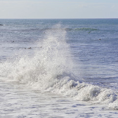 Wave which bursts, beach in Tahiti with surfers