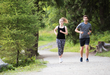 Fototapeta premium Beautiful young couple running outside in green nature.