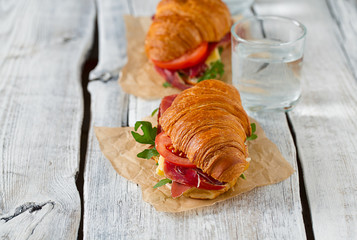croissants with argugula, jamon, cheese and tomato on wooden sur