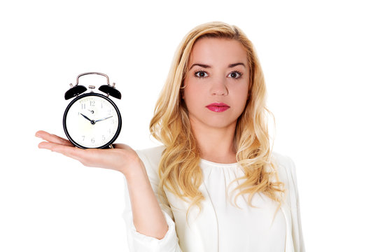 Blond woman showing alarm clock, isolated on white.