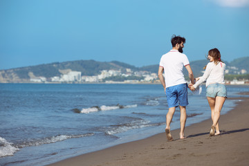 Fototapeta na wymiar Couple walking on beach. Young happy interracial couple walking on beach smiling holding around each other.