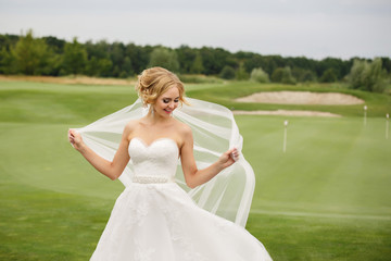 Wedding bride, portrait of beautiful bride with windy veil on green grass background and copy space for your text. Wedding concept