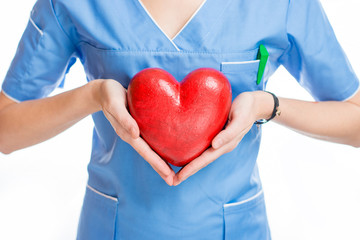 Female cardiologist in uniform holding red heart isolated on the white background. Close up view on...