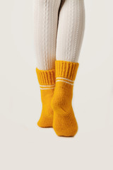 Female legs in white stockings and yellow knitted socks.