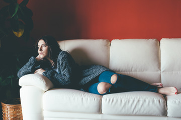 Young beautiful eastern woman relaxing lying on couch in livingroom - relax, serene, thinking concept