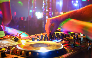 Close up of dj playing party music on modern cd usb player in disco club - Nightlife and entertainment concept - Defocused background with shallow depth of field and focus on buttons near mixing hand - obrazy, fototapety, plakaty