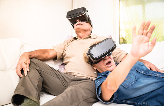 Senior couple having fun together with virtual reality headset - Retired people using new vr goggles glasses - New trends and technology concept - Focus on mature woman - Neutral apartment lights