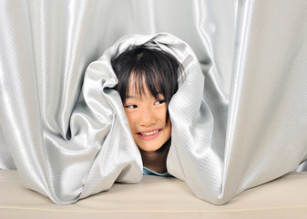 asian Little girl playing and peeking out from a curtain