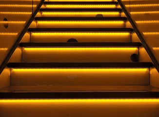 An illuminated or neon-colored stairway, striking background with yellow and orange colors. Funny mouseholes and led lighting.