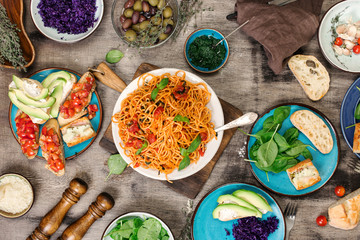 Pasta with different Italian dishes on the wooden table