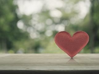 Fabric red love heart on wooden table over blur green tree background, soft tone, Valentines day concept