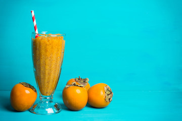 Persimmon smoothie with carrot and orange on wooden background