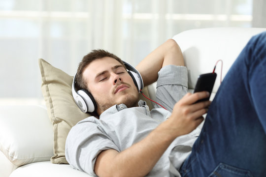 Man sleeping listening music at home