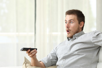 Obraz na płótnie Canvas Surprised man watching tv at home